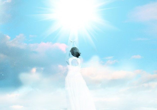 Woman reaching toward a light in the sky